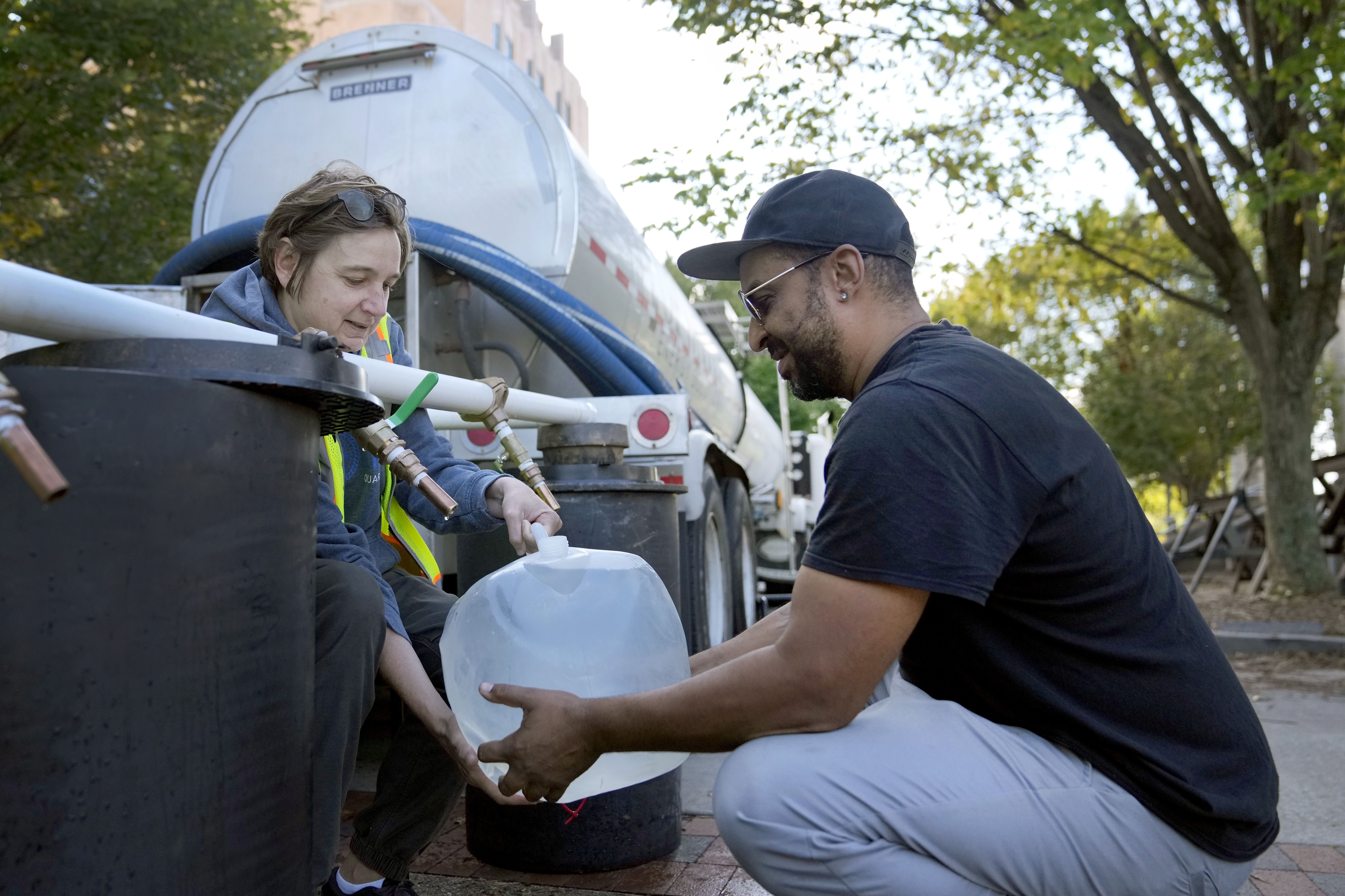 Reginald Klemz (R) fills a container of fresh water from a tanker with the help of volunteer Julie Koenke in the aftermath of Hurricane Helene, Asheville, North Carolina, U.S., October 2, 2024. /AP