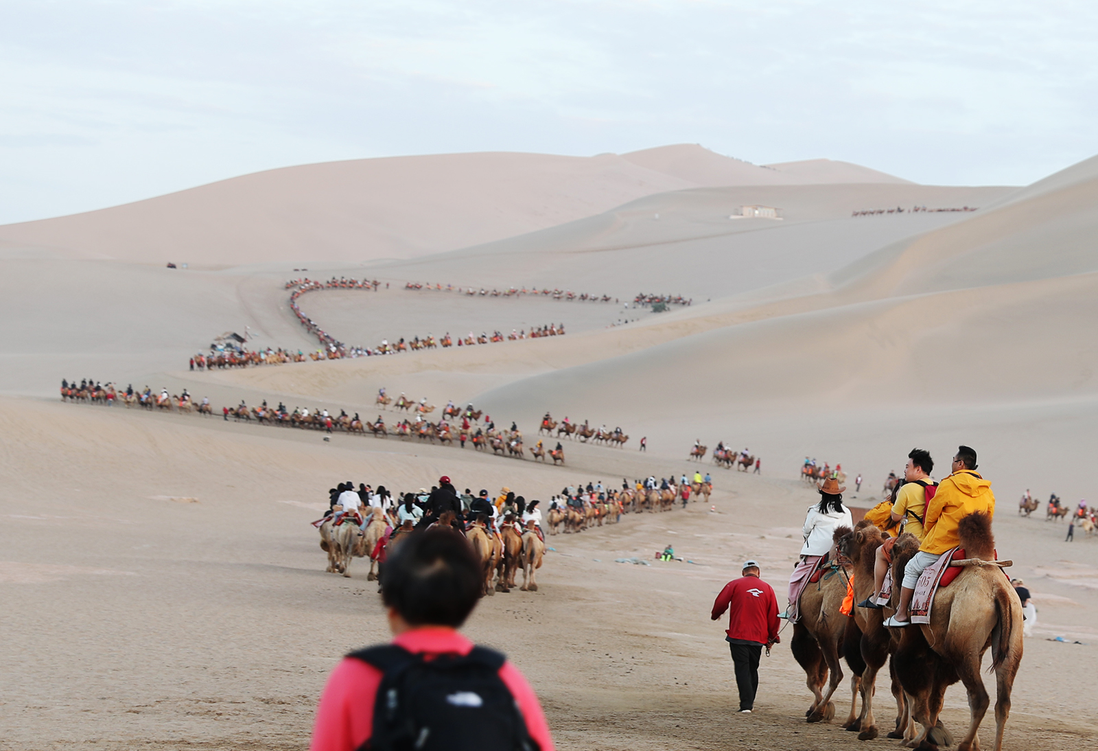 Visitors ride camels at Mingsha Mountain in Dunhuang, Gansu Province. /CGTN