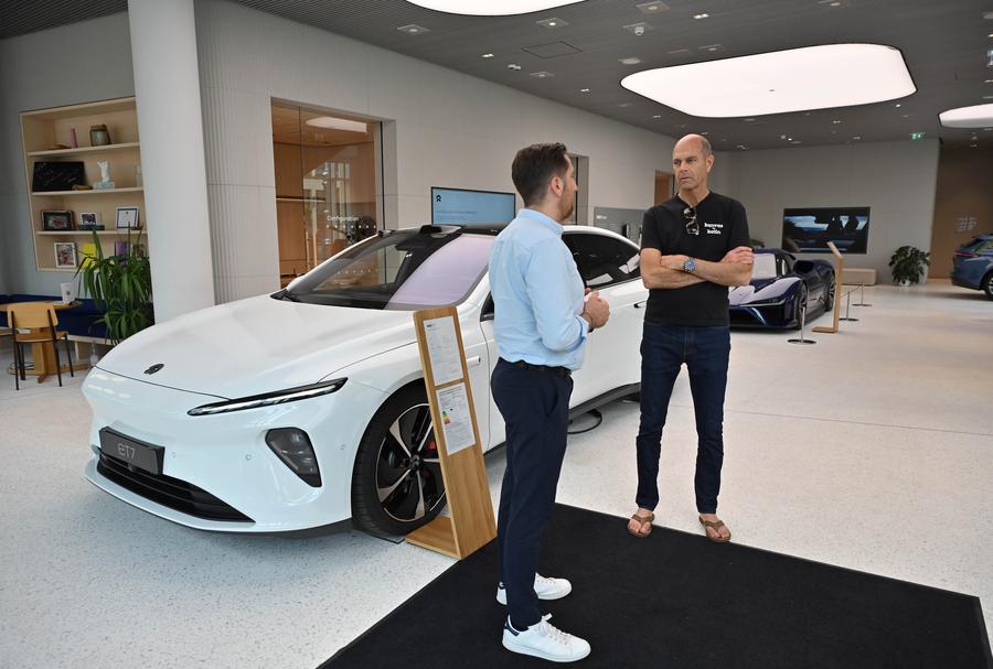 A staff member (L) explains the features of a vehicle to a visitor at a NIO House in Berlin, Germany, May 16, 2024. /Xinhua