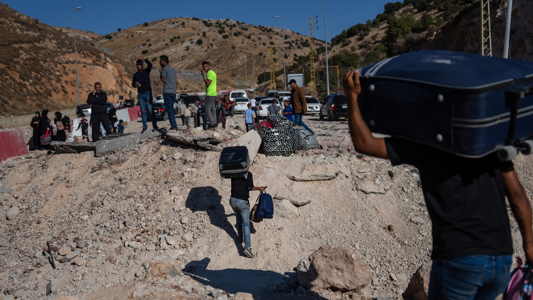 Men carry baggage through the crater from an Israeli air strike as they make their way across the border from Lebanon into Syria in Masnaa, Lebanon, October 5, 2024. /CFP