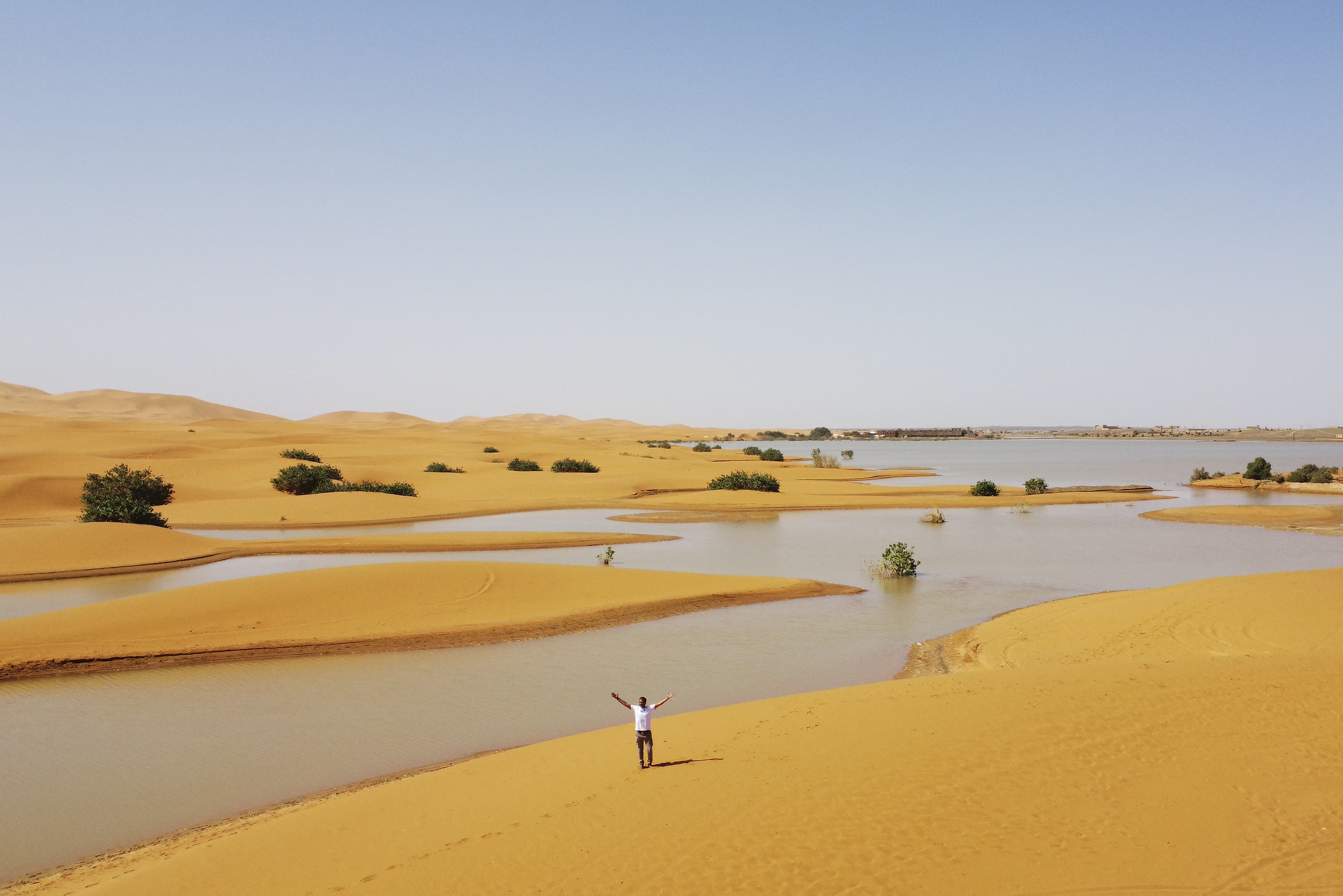 A man gestures as he walks on sand dunes next to a lake caused by heavy rainfall in the desert town of Merzouga, near Rachidia, southeastern Morocco, October 2, 2024. /AP 