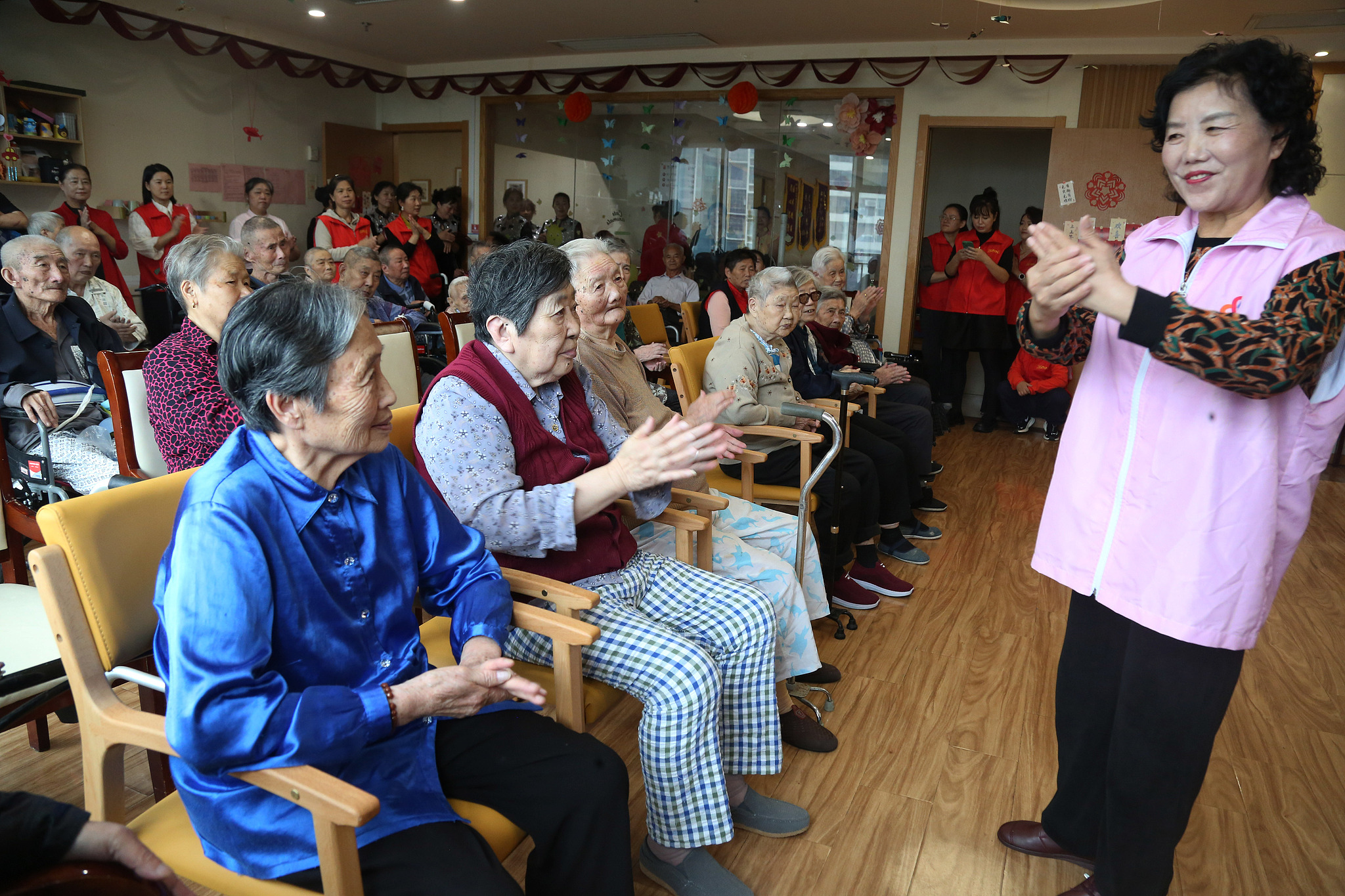 A senior volunteer performs a sign language dance for the elderly in a nursing home in Wuxi, east China's Jiangsu Province, October 6, 2024. /CFP