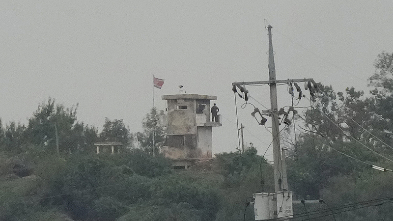 A soldier of the Democratic People's Republic of Korea stands guard at a military post as a DPRK flag flutters in the wind near the border, as seen from Paju, Republic of Korea, October 14, 2024. /CFP