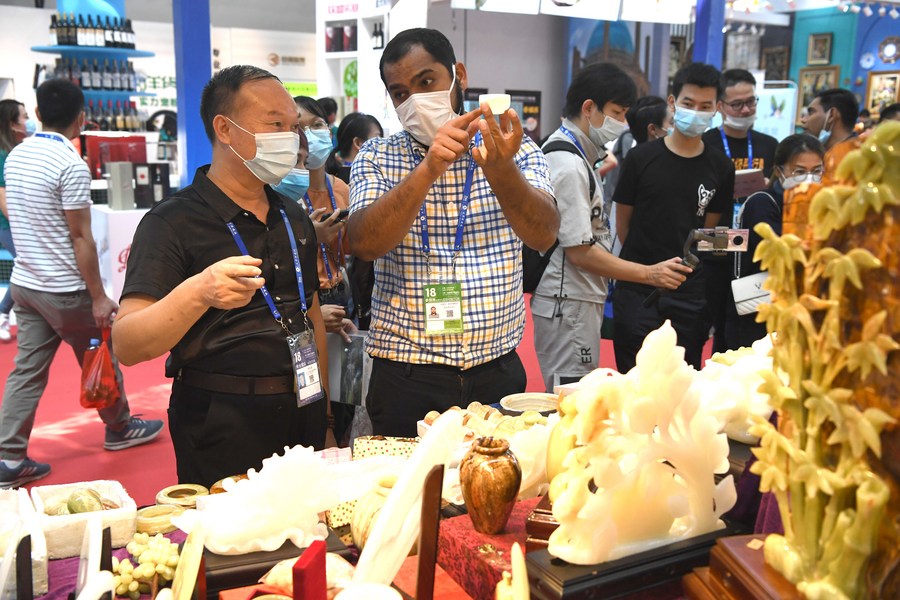 An exhibitor introduces a piece of jade artifact to a visitor at the 18th China-ASEAN Expo in Nanning, capital of south China's Guangxi Zhuang Autonomous Region, September 10, 2021. /Xinhua