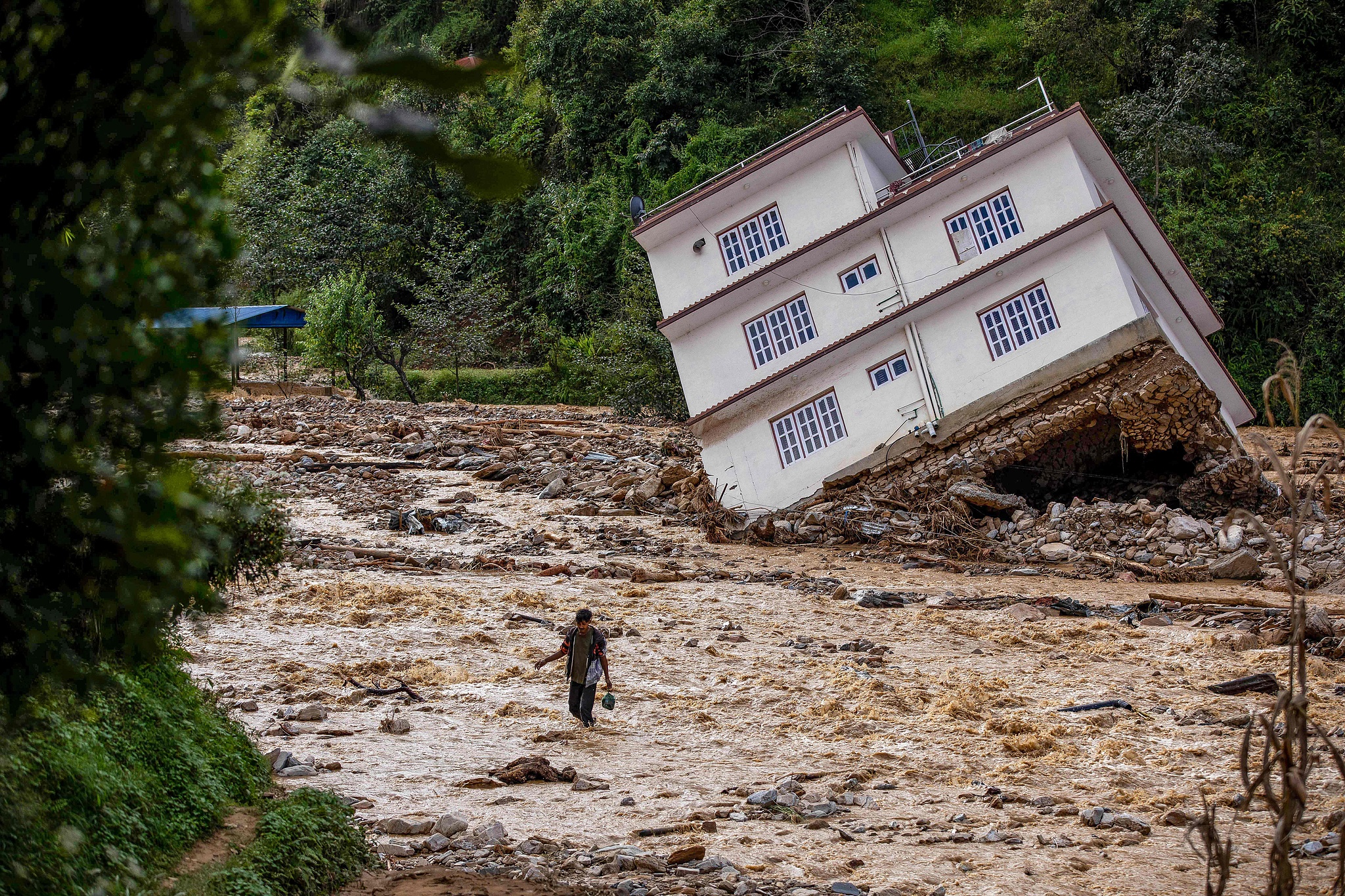 A man wades through the waters in the affected area of monsoon flooding in Roshi village of Kavre district, Nepal, September 30, 2024. /CFP