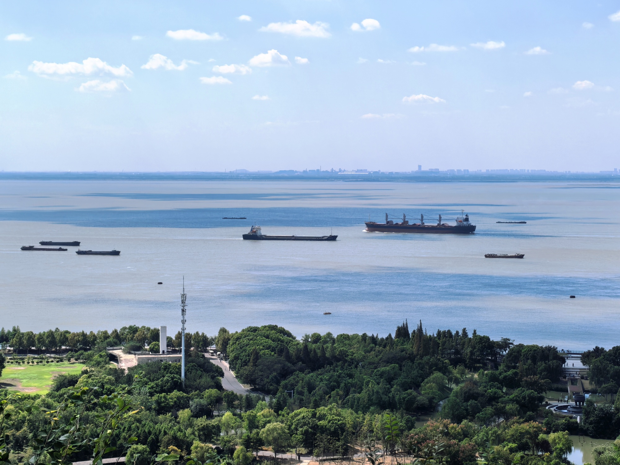 Cargo ships run on the Yangtze River next to Langshan, or Wolf Hill, in Nantong, east China's Jiangsu Province, on October 3, 2024. /CGTN