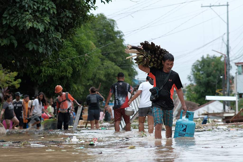 Residents carrying their belongings wade through a flooded street caused by heavy rains brought by Tropical Storm Trami, Bato Town, Camarines Sur Province, Bicol Region, the Philippines, October 24, 2024. /CFP