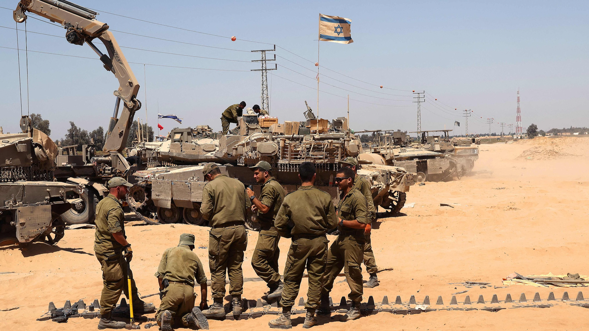 This picture taken from Israel's southern border with the Gaza Strip shows Israeli soldiers repairing the tracks of a tank, June 18, 2024. /CFP