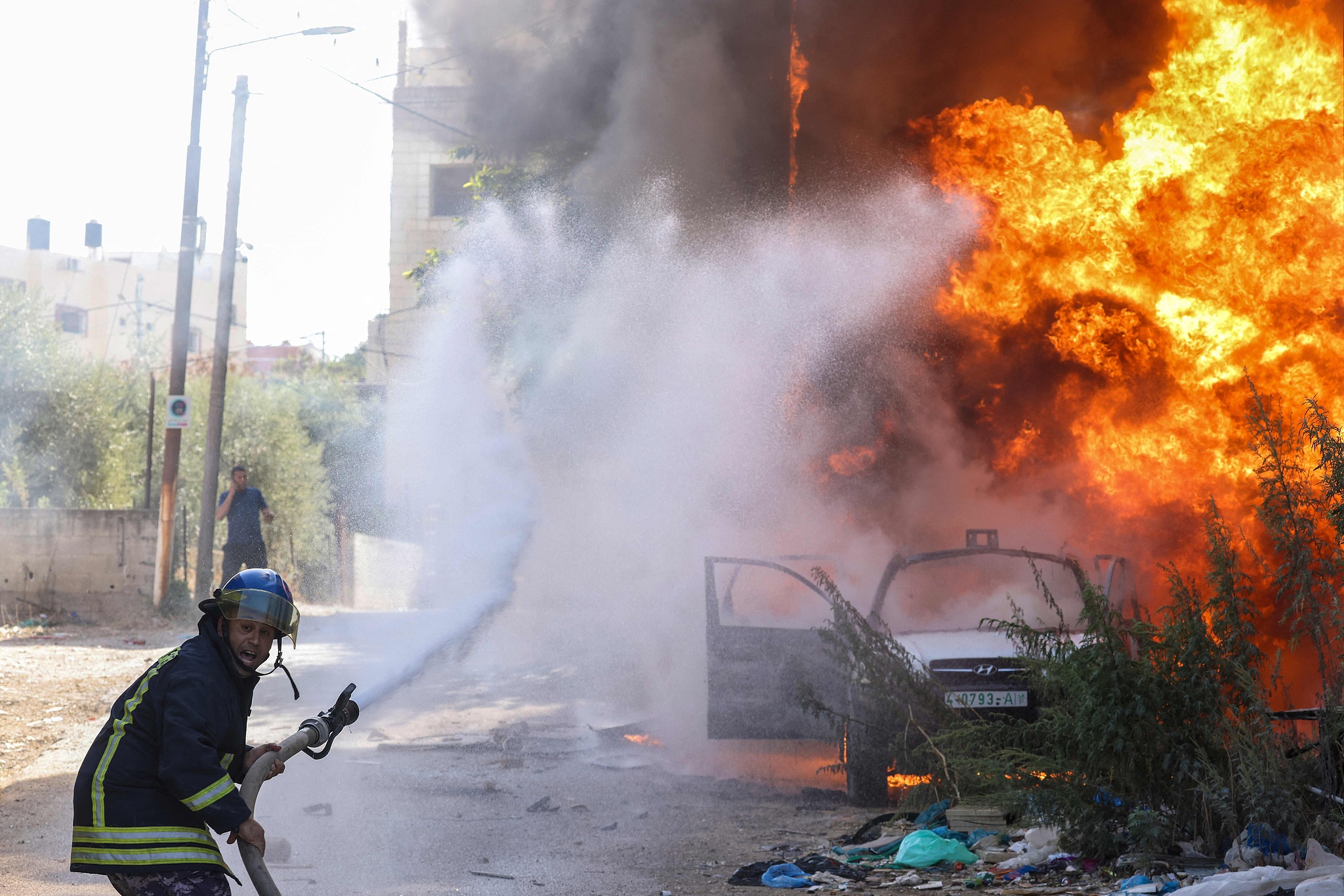 A Palestinian firefighter douses the flames engulfing a car following an Israeli raid in Tulkarem in the north of the occupied West Bank on October 26, 2024. /CFP