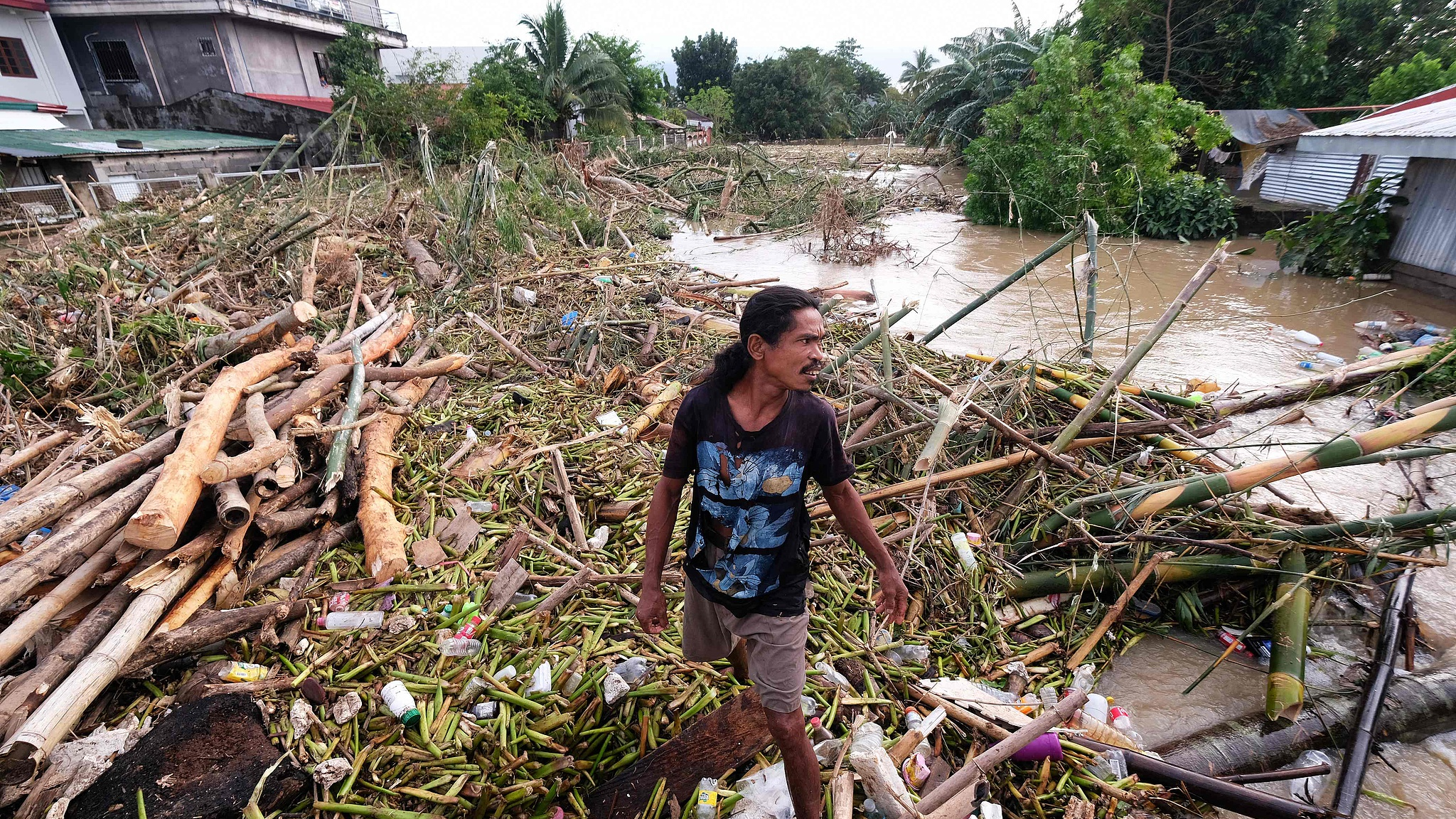 A man walks along the debris from the floods brought about by Tropical Storm Trami in Nabua, Camarines Sur, on October 25, 2024. /CFP