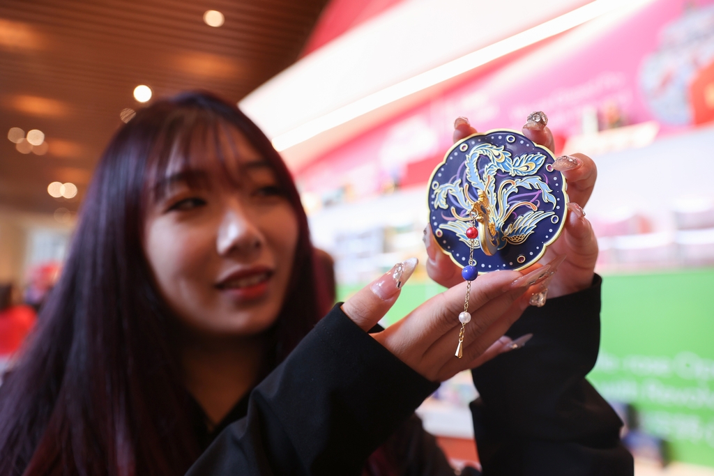 A photo taken on November 1, 2024 shows a woman holding a portable make-up mirror souvenir purchased at the National Museum of China in Beijing. /CFP