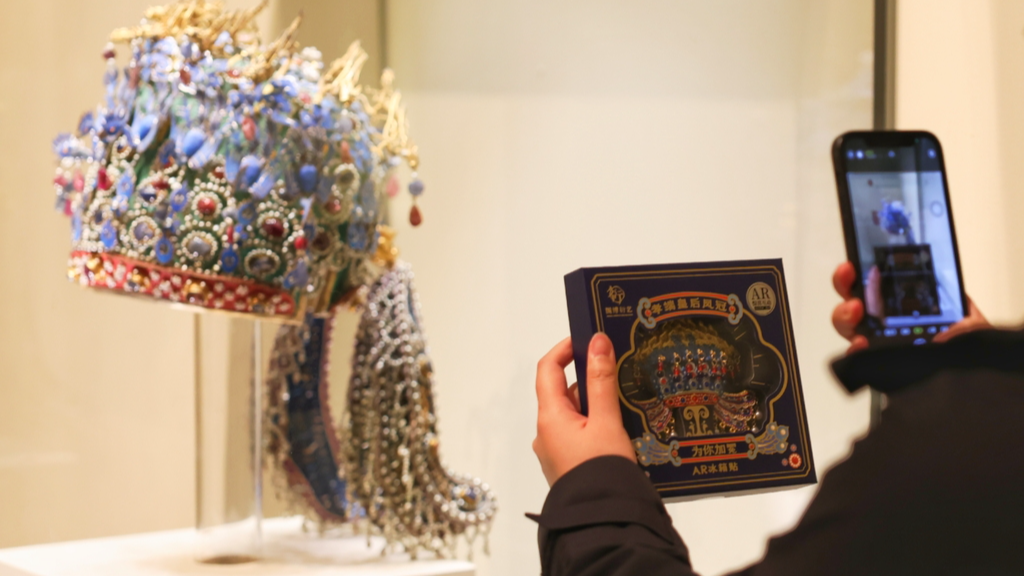 A photo taken on November 3, 2024 shows a visitor photographing a phoenix crown magnet with the actual crown in the background at the National Museum of China in Beijing. /CFP