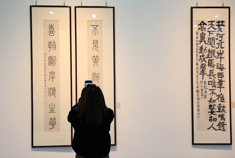 A visitor takes photo of a calligraphic work at the 11th Cross-Strait Chinese Character Culture & Art Festival in Zhengzhou, central China's Henan Province, December 22, 2021. /CFP