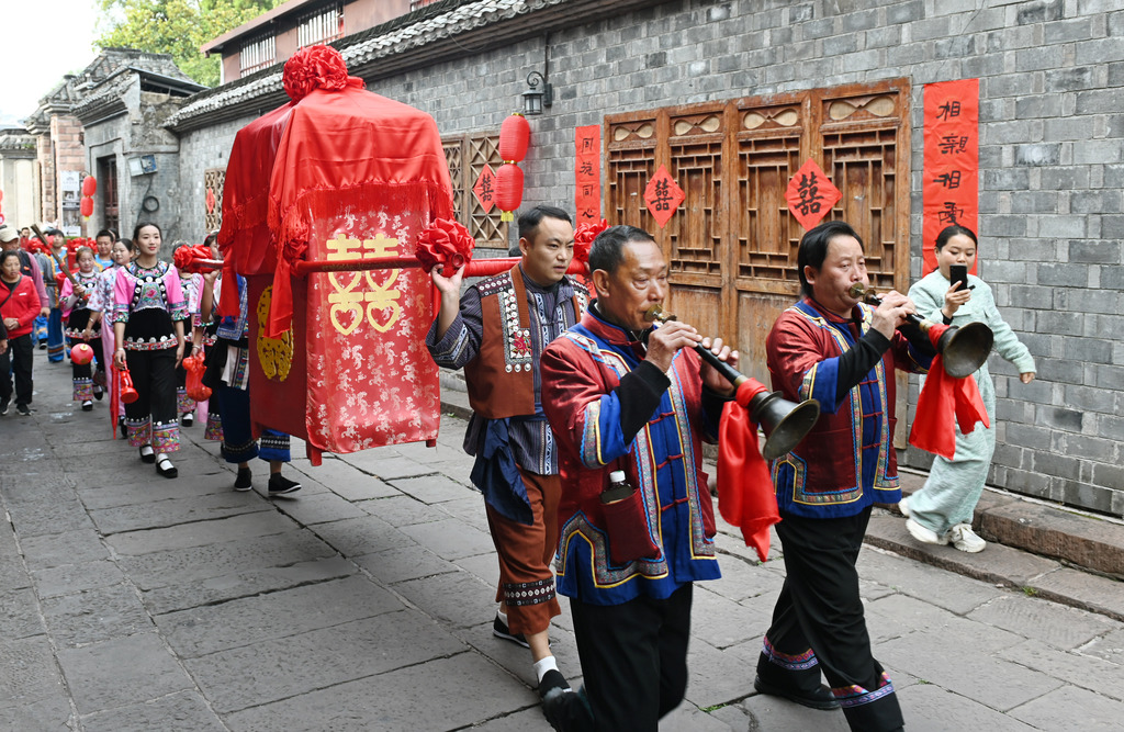 A total of 100 newlywed couples dressed in ethnic wedding attire attend a collective wedding celebration in an ancient town in Fenghuang County of Xiangxi Tujia and Miao Autonomous Prefecture, Hunan Province, November 11, 2024. /CFP  