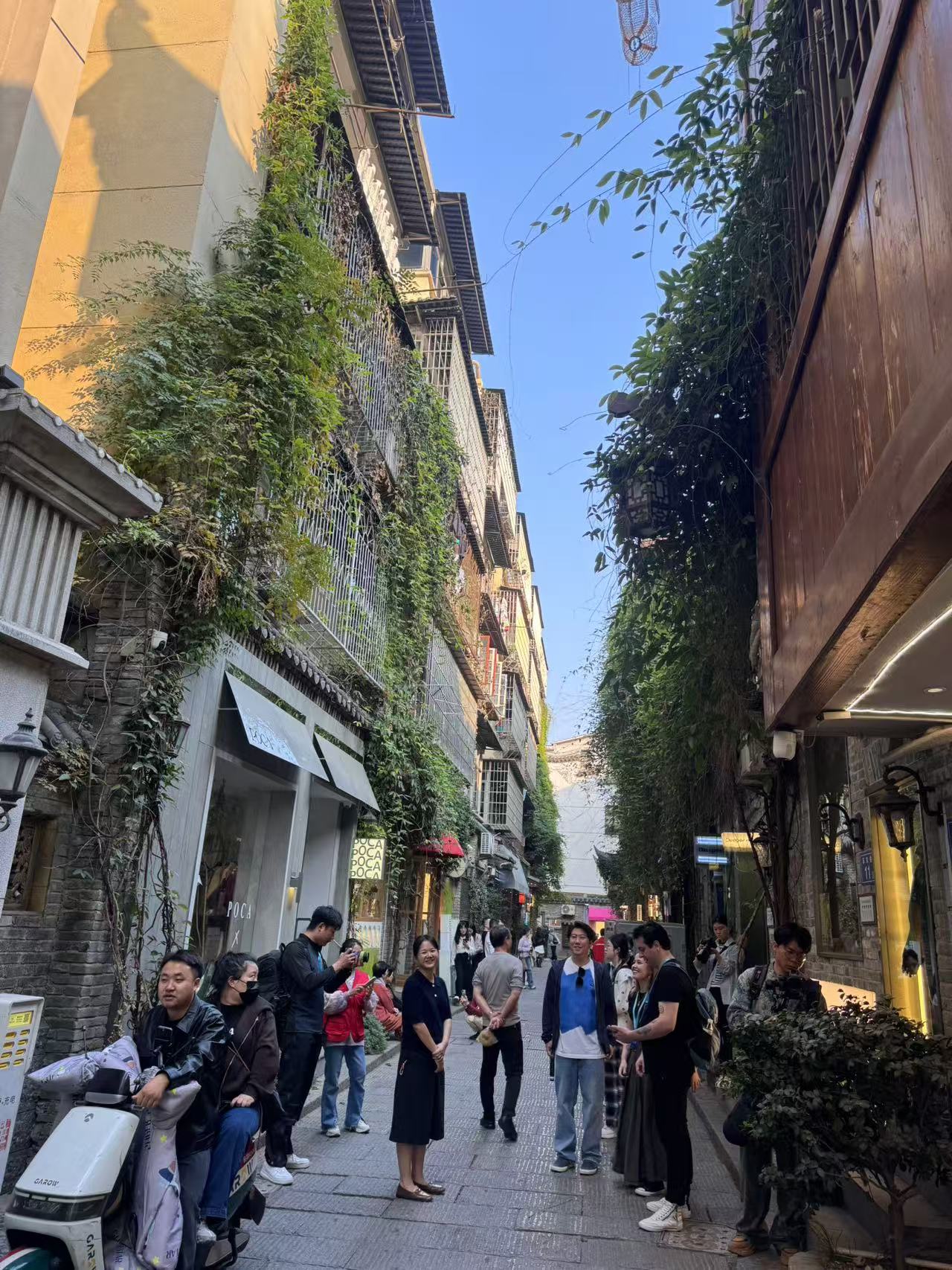 As the sun sets, visitors stroll along the ancient street, while locals ride on their motorbikes. The glittering lights from the shops illuminate the historic buildings, where green plants adorn the walls, blending nature with culture. Zhou Li/CGTN