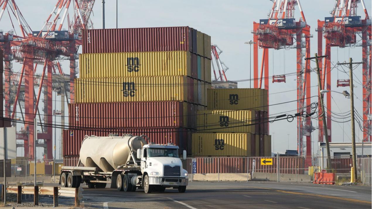 A truck drives past shipping containers at Port Newark, New Jersey, U.S., October 4, 2024. /CFP