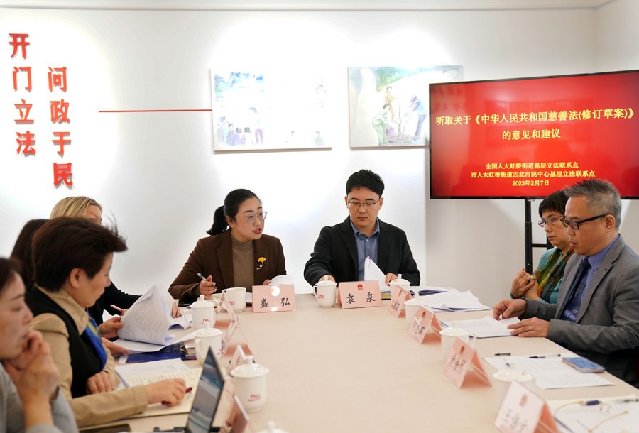 Sheng Hong (4th R), a deputy to the National People's Congress and Party chief of a residential community in the Hongqiao Subdistrict, listens to comments and suggestions of a draft revision to the Charity Law at a civic center in east China's Shanghai, February 7, 2023. /Xinhua