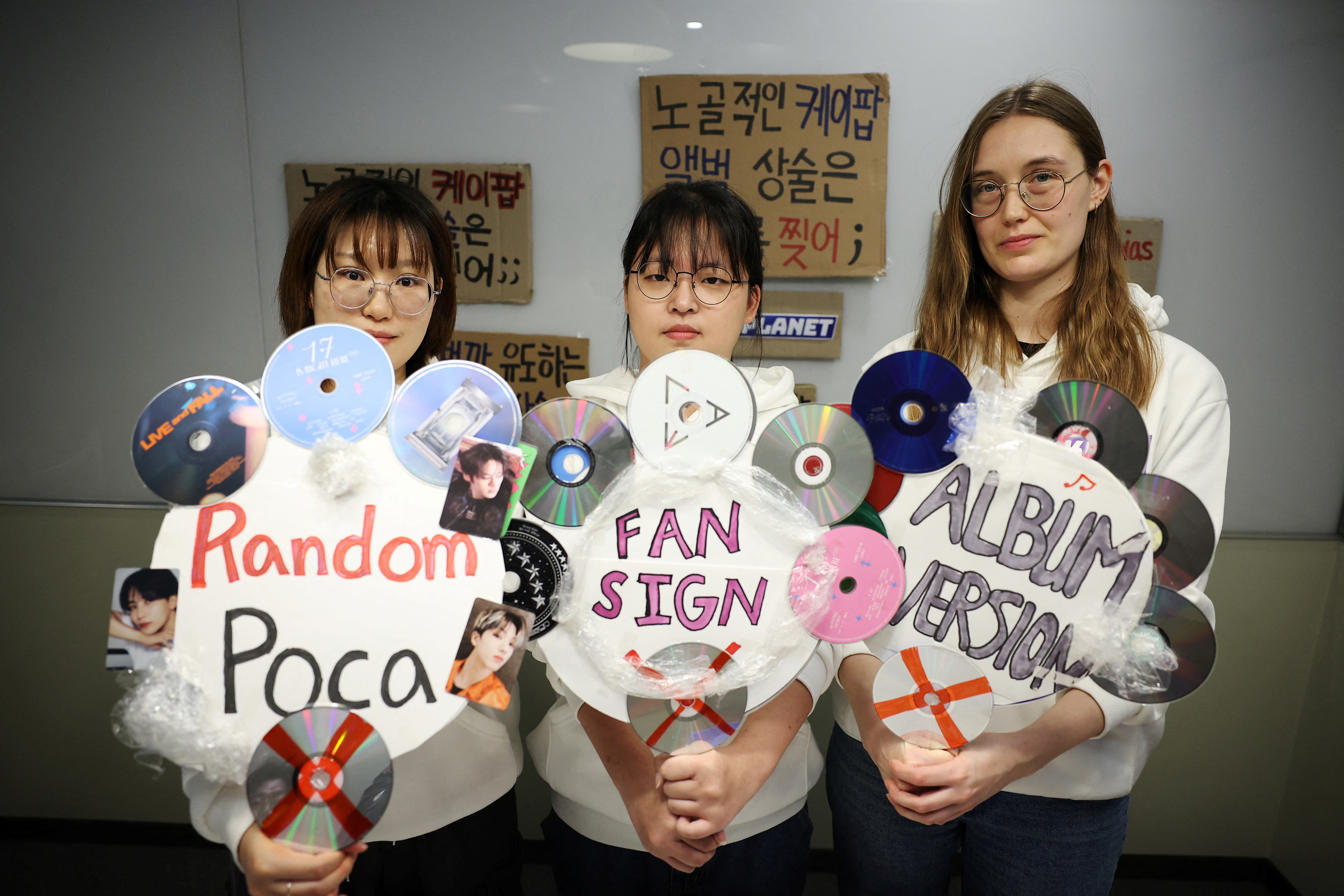 L-R: Kpop4planet activists Park Jin-hui, Kim Na-yeon and Roza de Jong pose for photographs with signs made of K-pop idol fans' items and CDs that will be used in a march ahead of the fifth session of the Intergovernmental Negotiating Committee on Plastic Pollution, in Seoul, South Korea, November 13, 2024. /Reuters