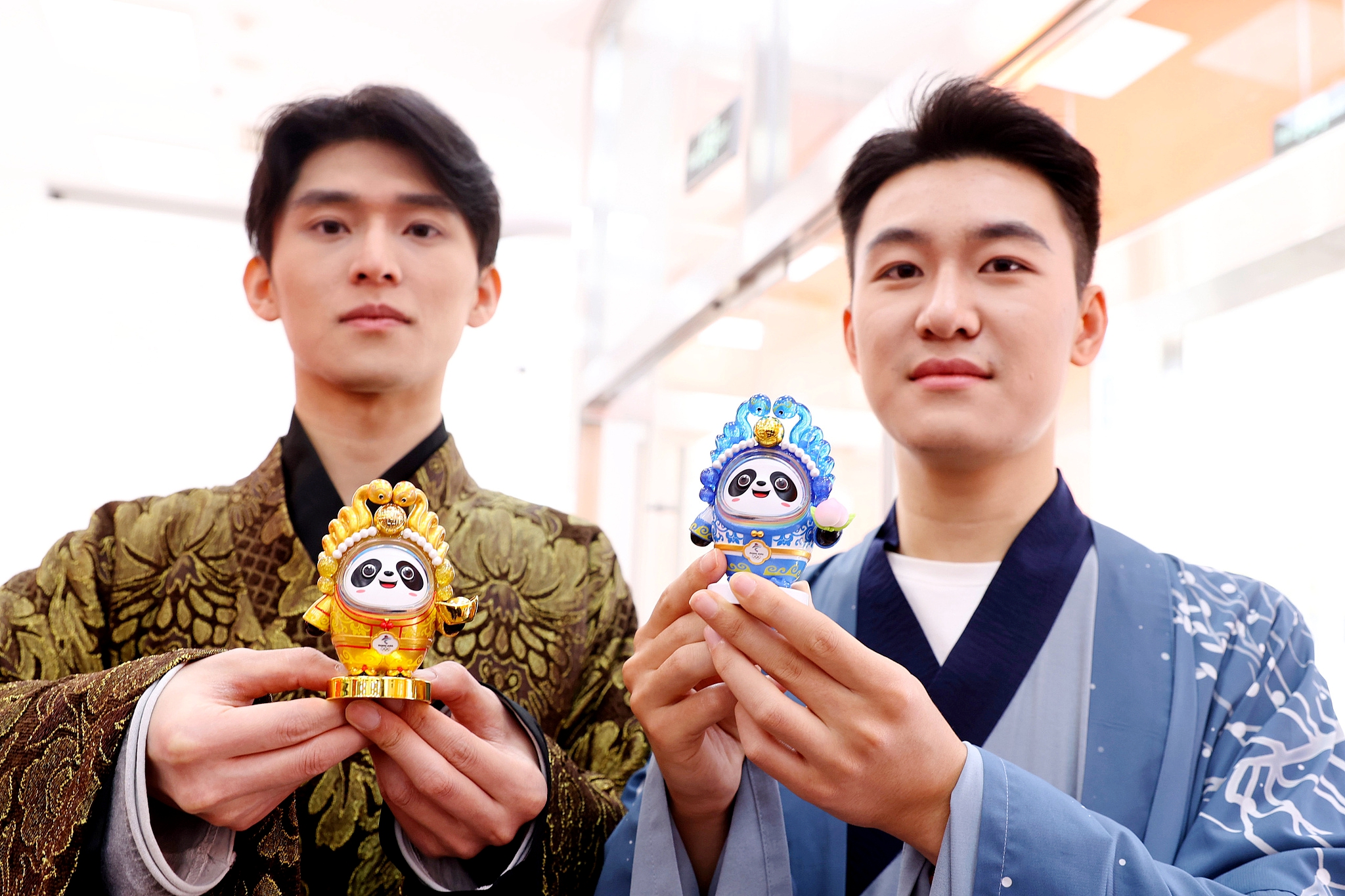 Two men pose for photos with snake-themed Bing Dwen Dwen products in Beijing on November 22, 2024. /CFP