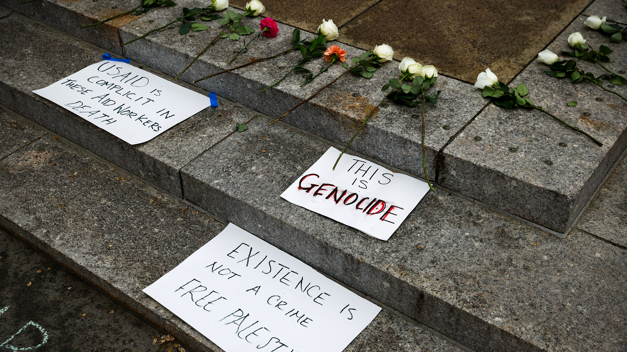 Flowers and signs lie on the ground in front of the U.S. Agency for International Development building at a vigil for aid workers killed in Gaza, in Washington, D.C., U.S., April 11, 2024. /CFP