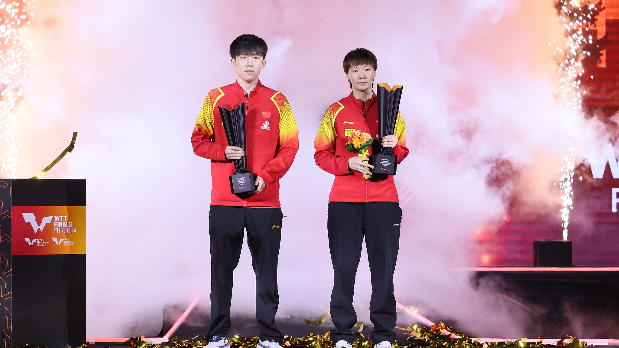 Wang Chuqin (L) and Wang Manyu celebrate with their trophies at WTT Finals in Fukuoka, Japan, November 24, 2024. /CFP