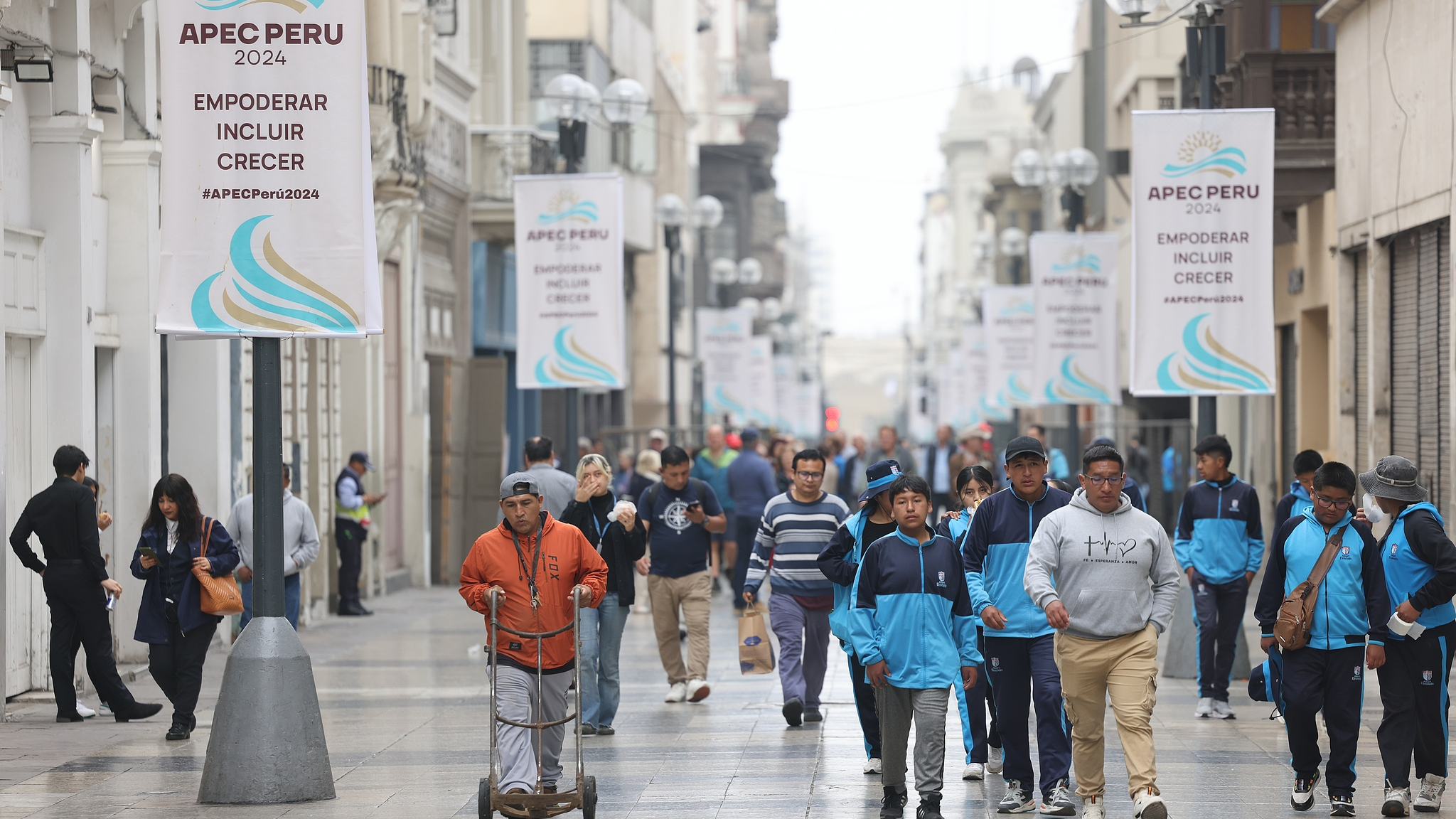 People walk on the street with logos of the 31st APEC Economic Leaders' Meeting hanging on both sides in Lima, capital of Peru, November 12, 2024. /CFP