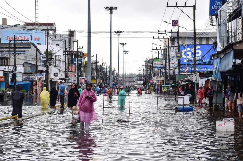 People wade through flood waters following heavy rain in Thailand's southern province of Narathiwat on November 27, 2024. /AFP