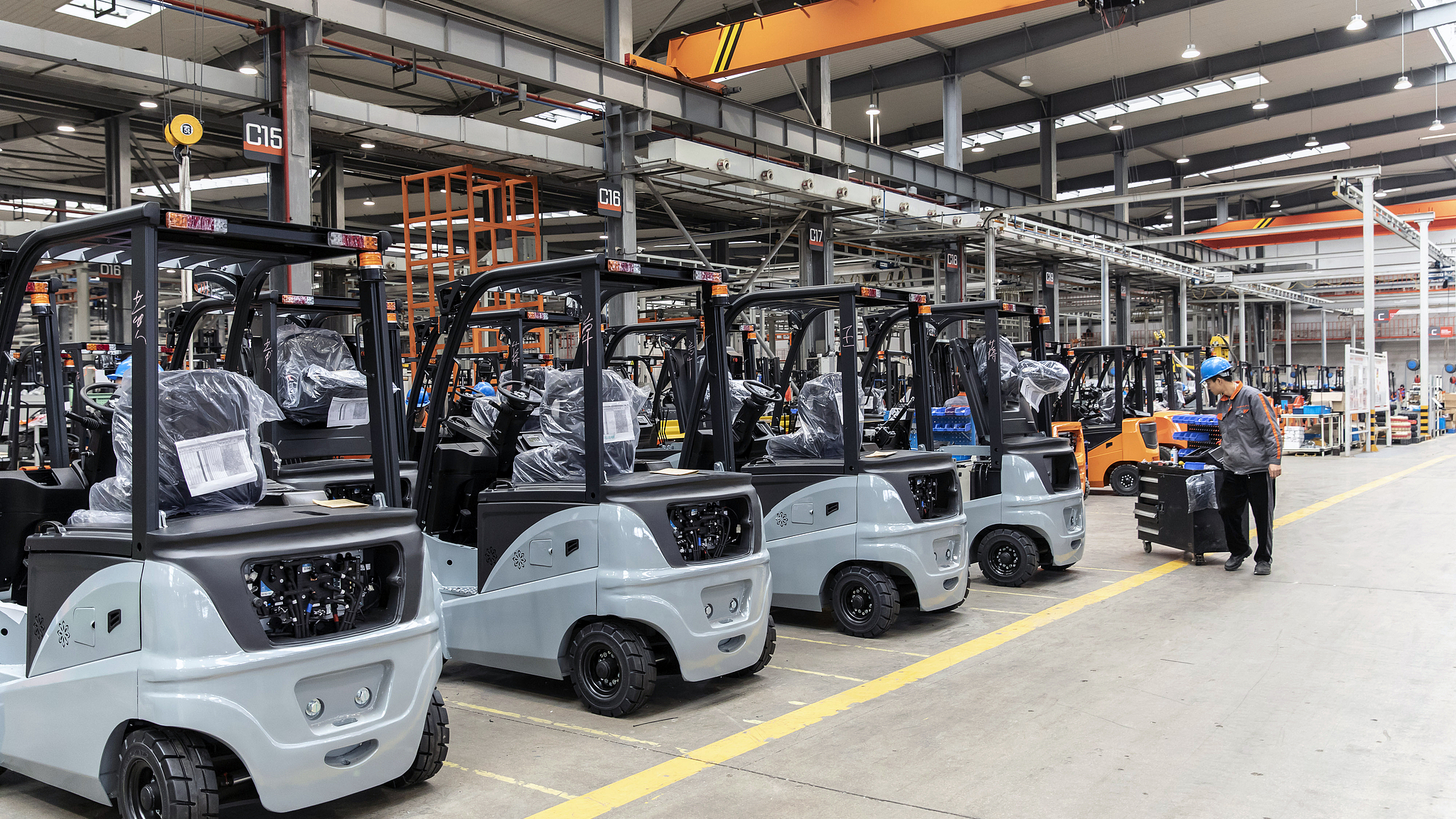 An employee pulls a cart past electric forklifts in a factory in Huzhou, Zhejiang Province, China, on April 14, 2021. /CFP