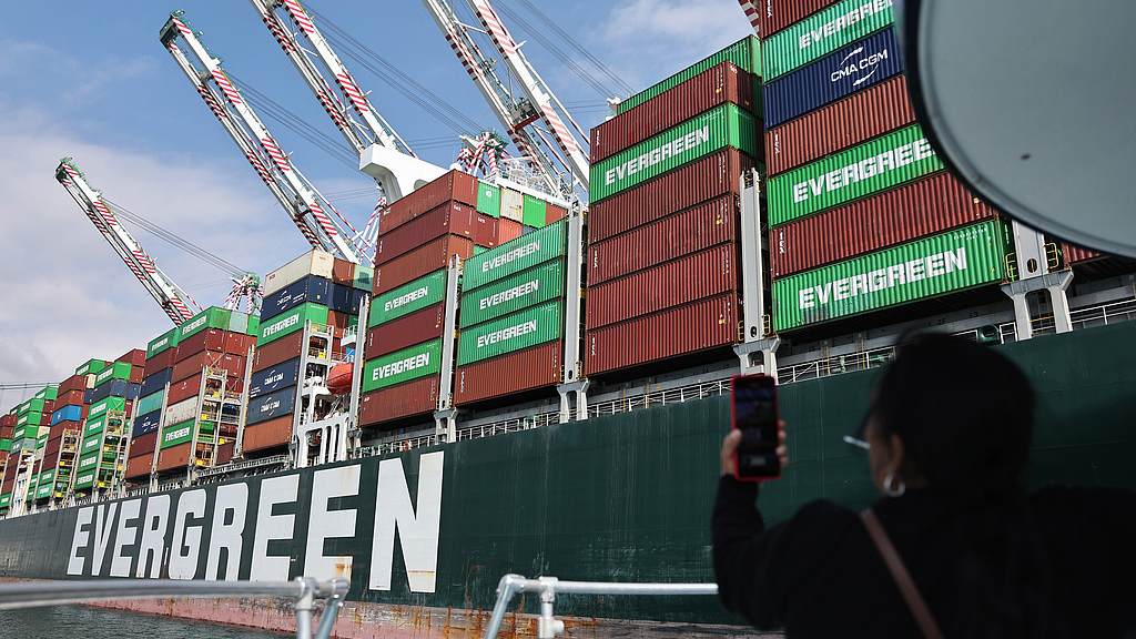 A tourist takes photos on a boat while passing shipping containers at the Port of Los Angeles, September 20, 2024. /CFP