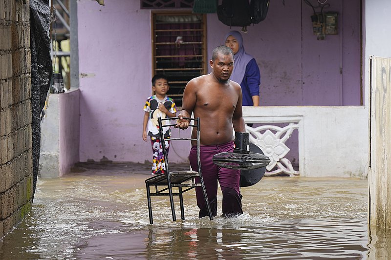 A man removes a chair and a fan from his flooded house in Tumpat, Malaysia, December 3, 2024. /CFP 