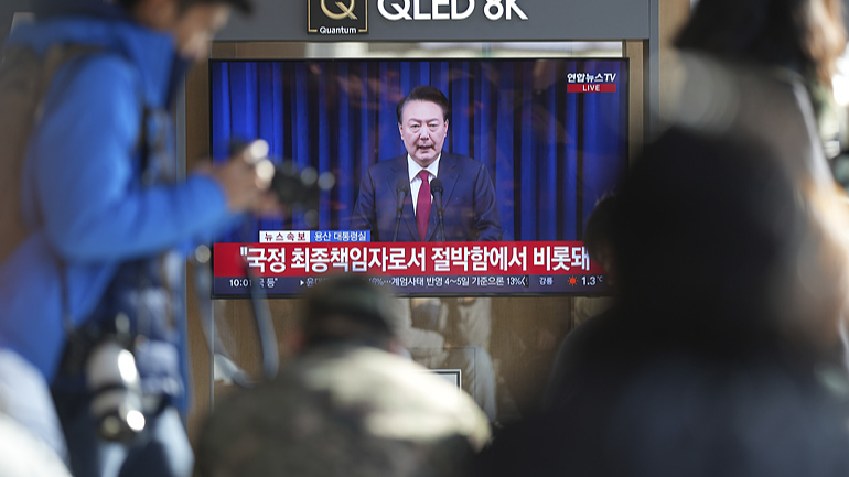 People watch a TV screen showing the live broadcast of South Korean President Yoon Suk-yeol's announcement at the Seoul Railway Station in Seoul, December 7, 2024. /CFP