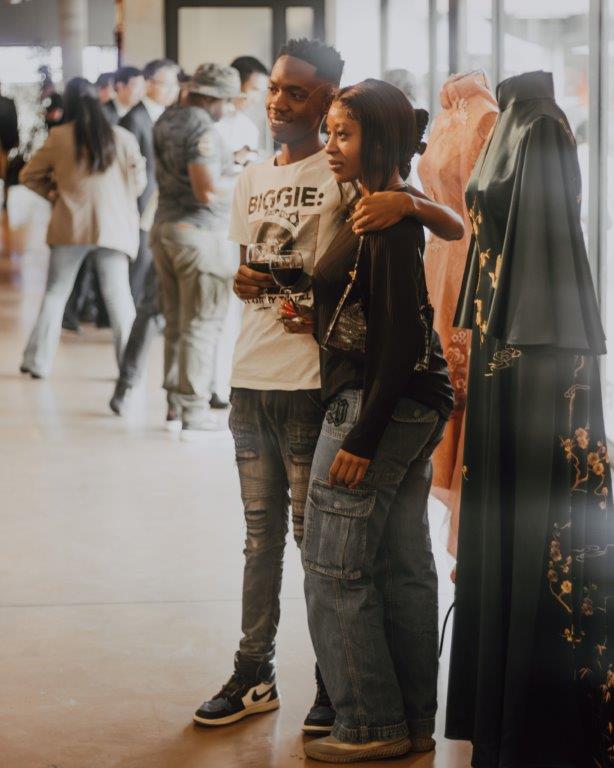 Visitors pose for pictures with traditional dresses on display at the 