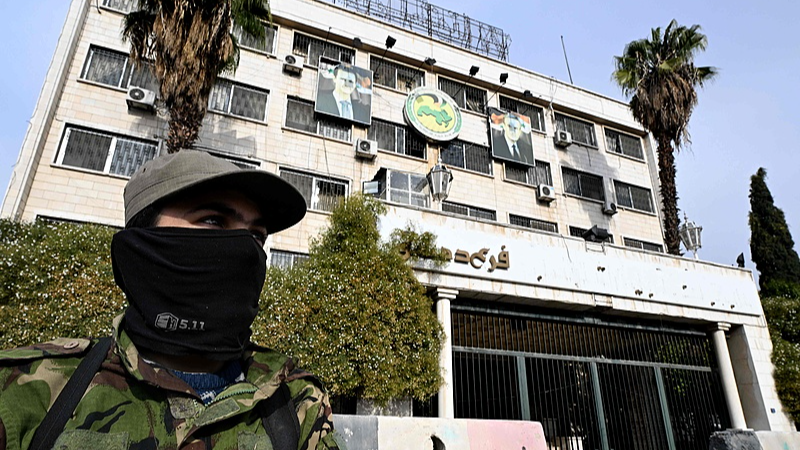 The portraits of toppled Syrian President Bashar al-Assad and his late father Hafez al-Assad hang outside the Baath party offices in Damascus as a fighter stands guard, December 12, 2024. /CFP