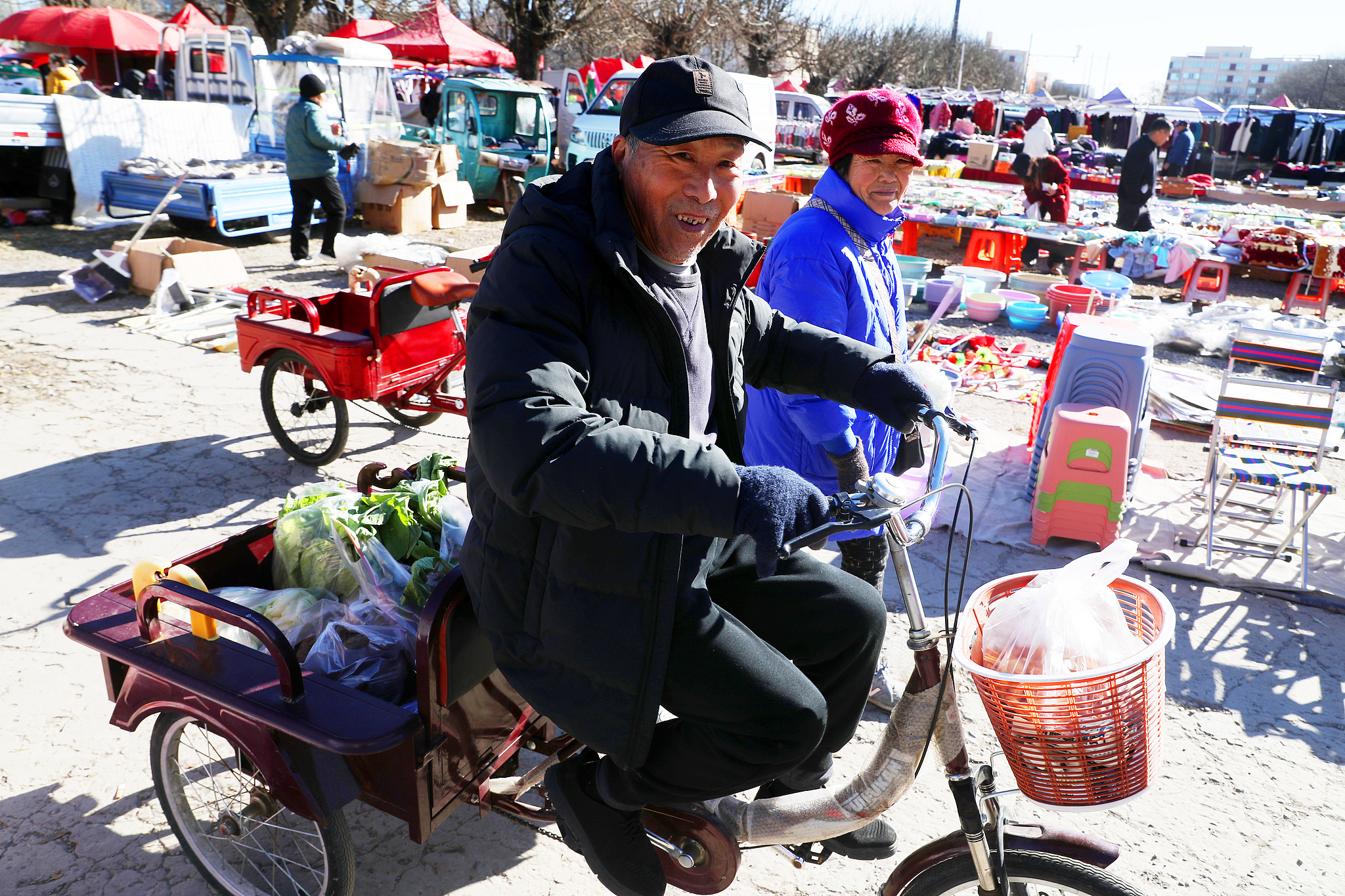 A shopper rides a tricycle loaded with vegetables at a rural open-air market in Huoxian County, Tongzhou District, Beijing, December 2, 2024. /CFP