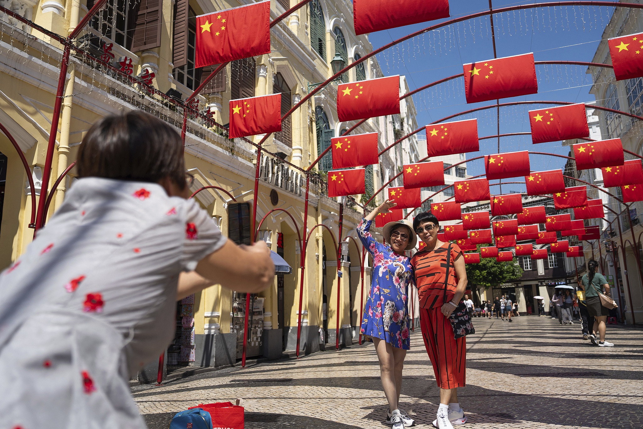 Tourists pose for photos at Senado Square with Chinese national flags during the Chinese National Day holidays in Macao, China, October 7, 2024. /VCG