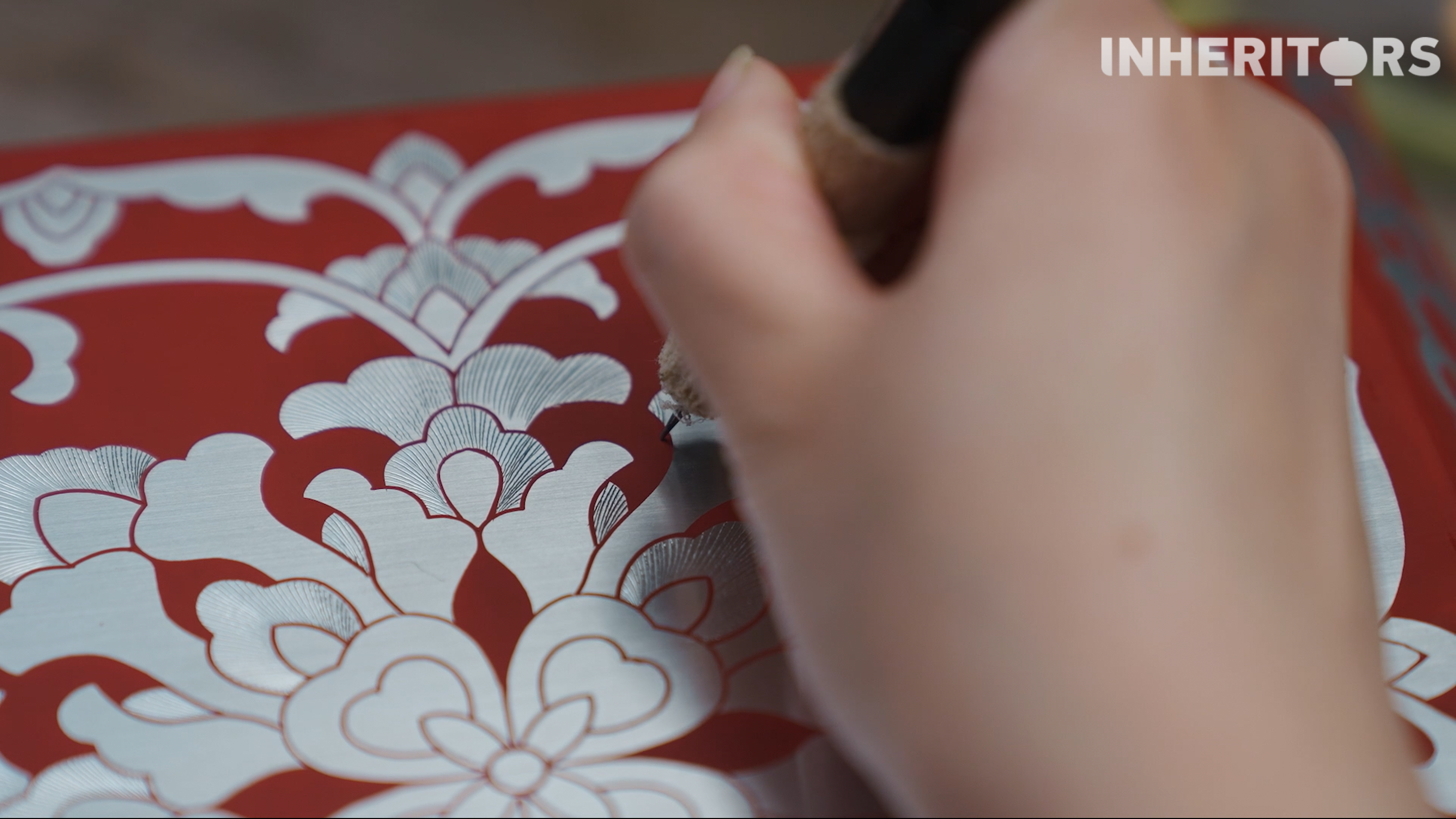 An artisan uses a specially designed engraving needle to draw thread-like lines into the metal foil inlaid in a piece of lacquerware. /CGTN