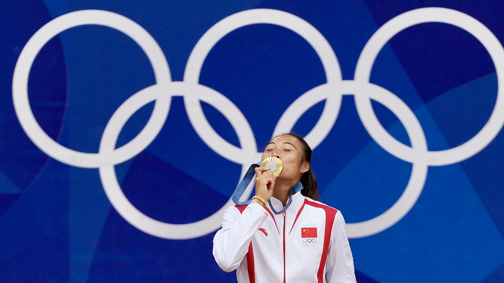 China's Zheng Qinwen kisses her gold medal after defeating Croatia's Donna Vekic during the Women's Singles tennis final at the Roland Garros stadium in Paris, France, August 3, 2024. /CFP