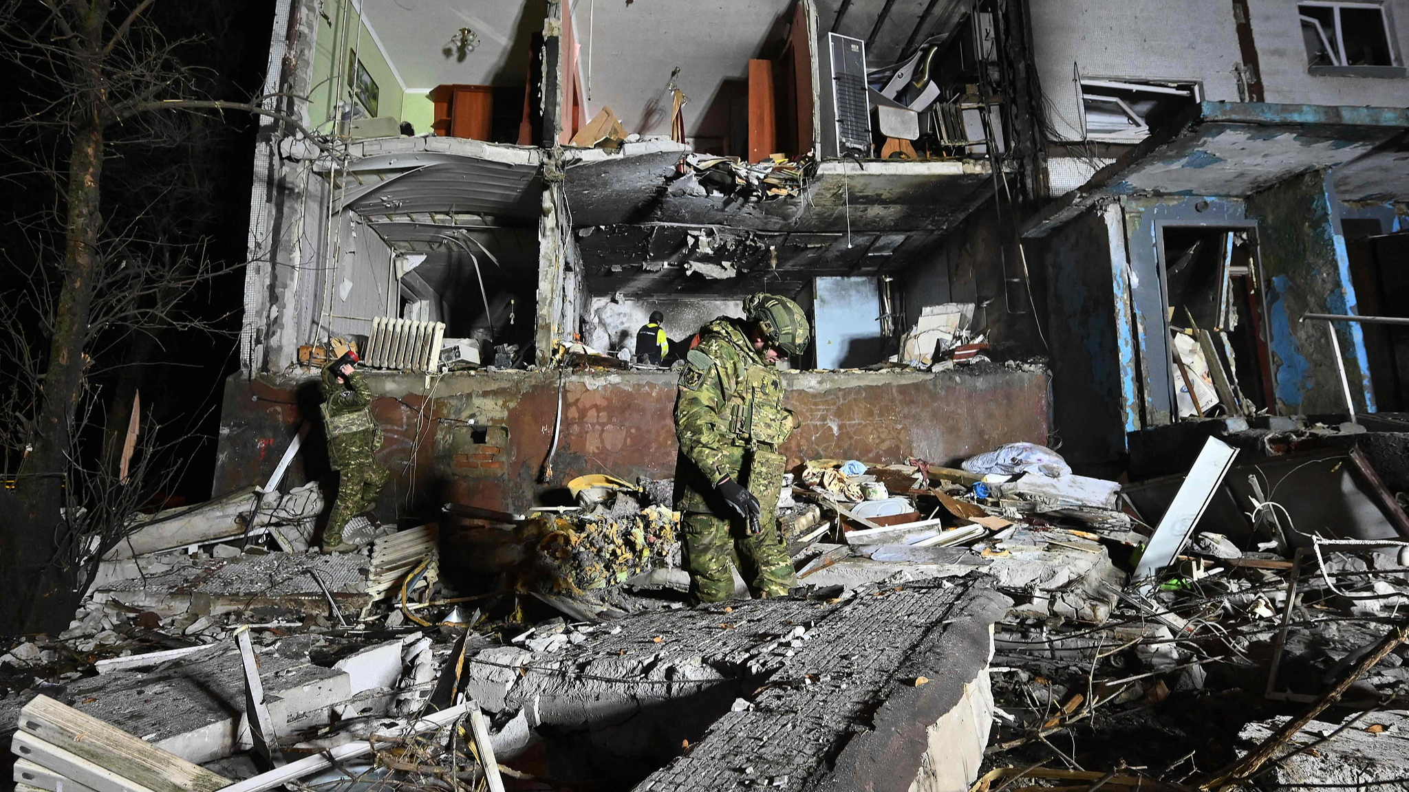 Ukrainian law enforcement officers stand among rubble next to a damaged residential building following a drone attack in Kharkiv, Ukraine, December 20, 2024. /CFP