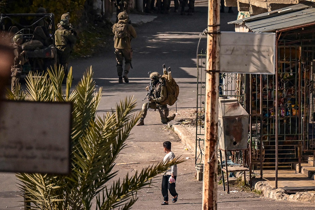 A child looks on as Israeli soldiers patrol in the Syrian town of Jubata al-Khashab, in the UN-patrolled buffer zone in the Israeli-occupied Golan Heights, December 20, 2024. /CFP