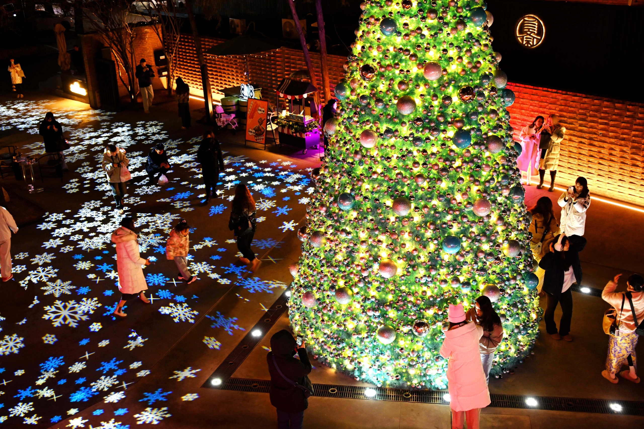 A photo taken on December 23, 2024, shows a Christmas tree and snowflake lights dazzling visitors in Sanlitun, Beijing. /IC