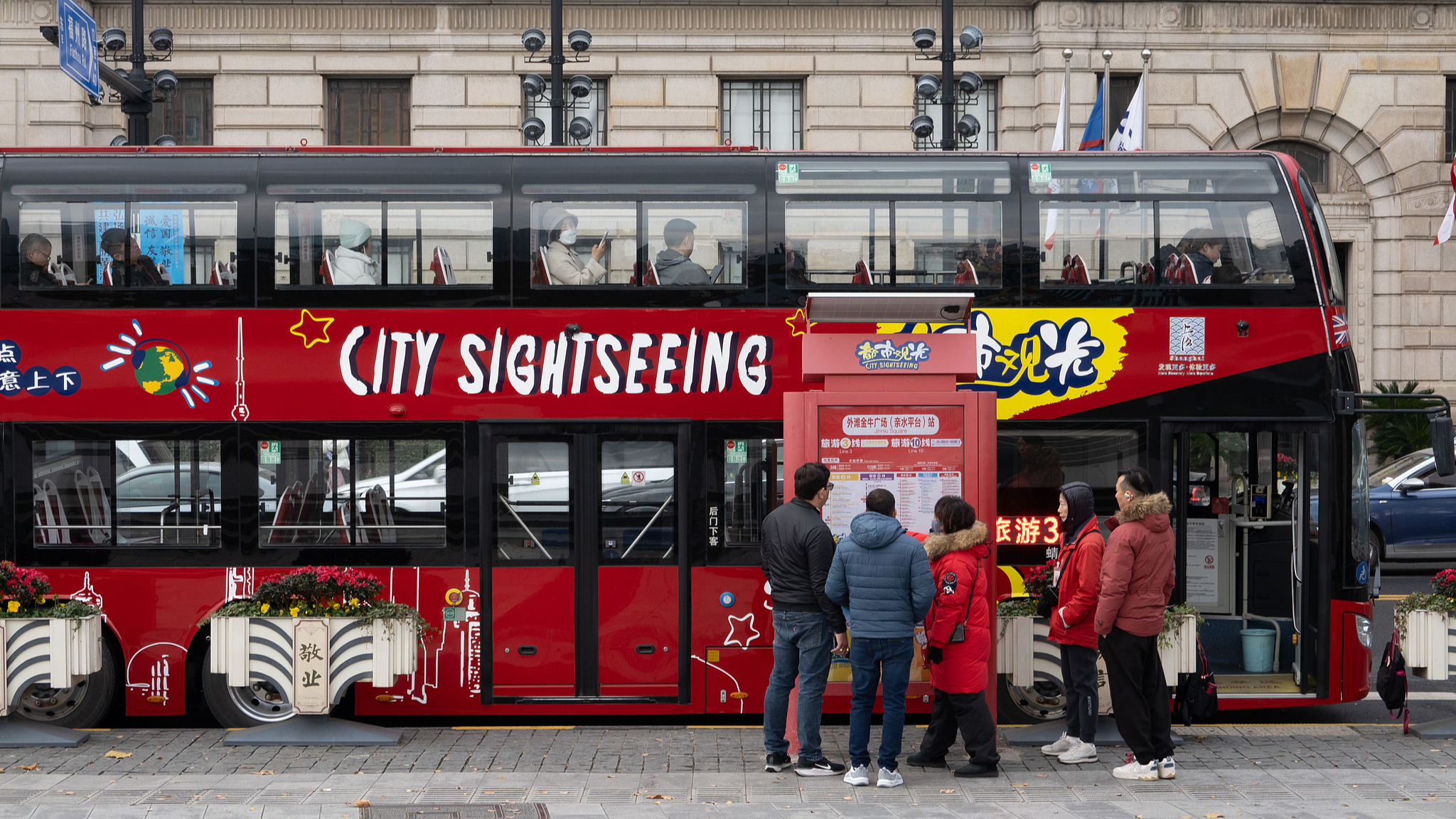 Foreign tourists consult a staff member in front of a sightseeing bus at the Bund in Shanghai, China, December 18, 2024. /CFP