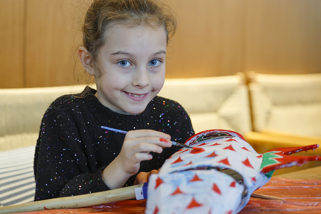 A dutch girl experiences drawing and making a fish lantern in Xixinan Ancient Village on December 26, 2024. /CFP