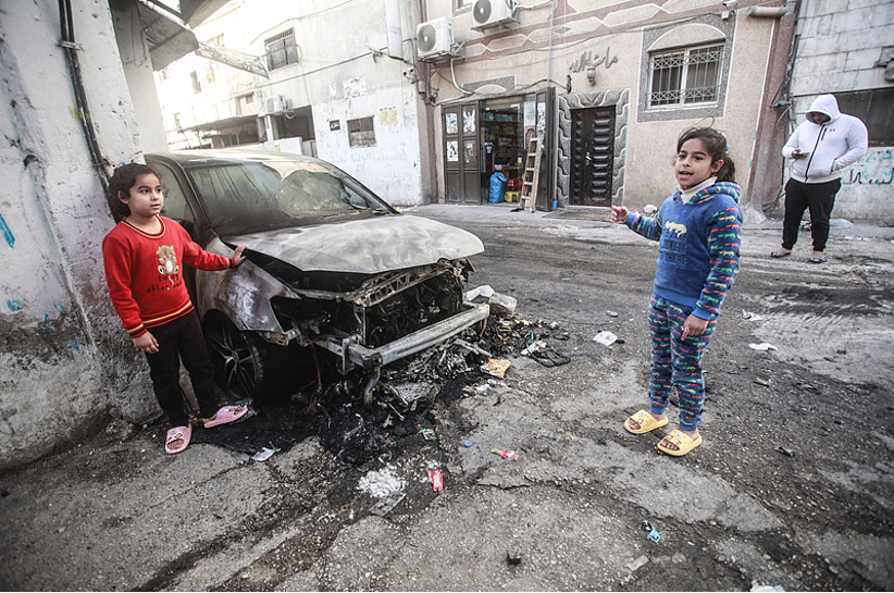 Palestinian girls Layan and Leen Shatara stand next to their father's burned-out car during clashes between Israeli occupation forces and Palestinians in Askar refugee camp, December 27, 2024. /CFP