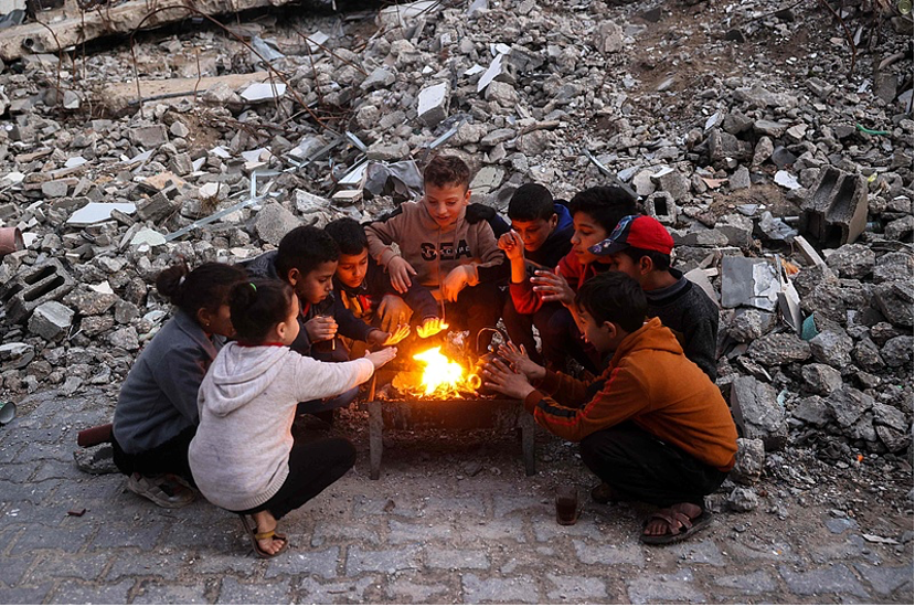 Children warm by the fire at the Bureij camp for displaced Palestinians on December 30, 2024. /CFP