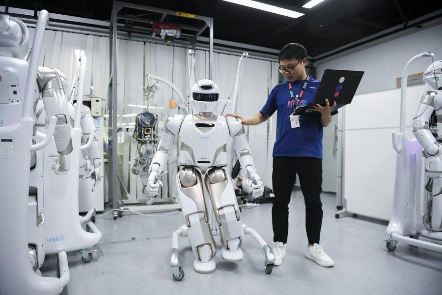 A staff member conducts tests on a Walker X humanoid robot at a sci-tech company in Shenzhen, south China's Guangdong Province, June 26, 2024. /Xinhua