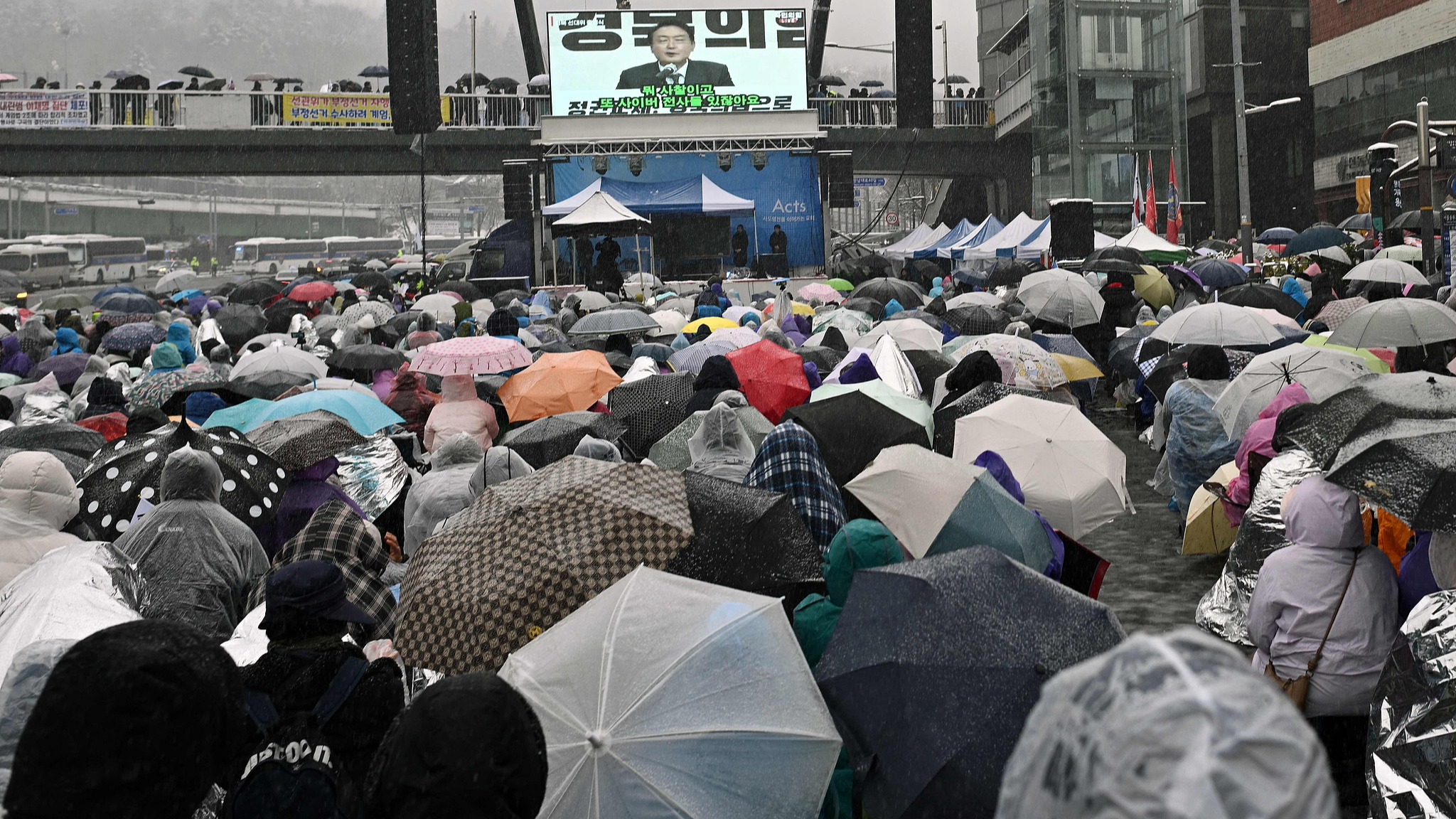 Supporters of impeached South Korean President Yoon Suk-yeol look at a screen showing footage of Yoon as they take part in a rally near his residence as snow falls in Seoul on January 5, 2025. /CFP