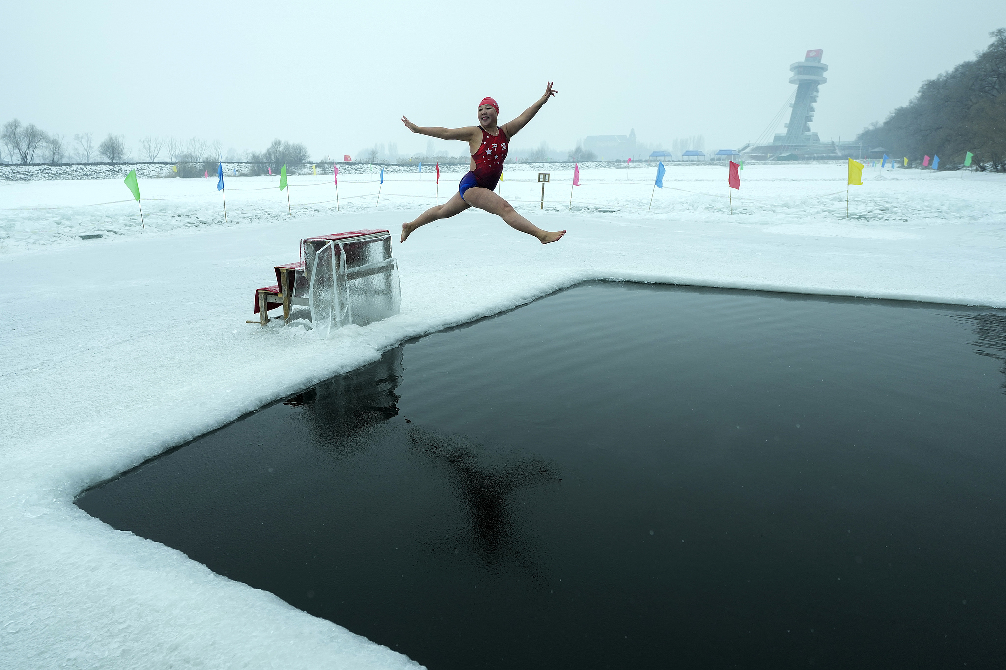 A woman leaps into the air as she jumps into a pool carved out of the frozen Songhua River in Harbin, Heilongjiang Province on January 7, 2025. /Andy Wong/AP/VCG