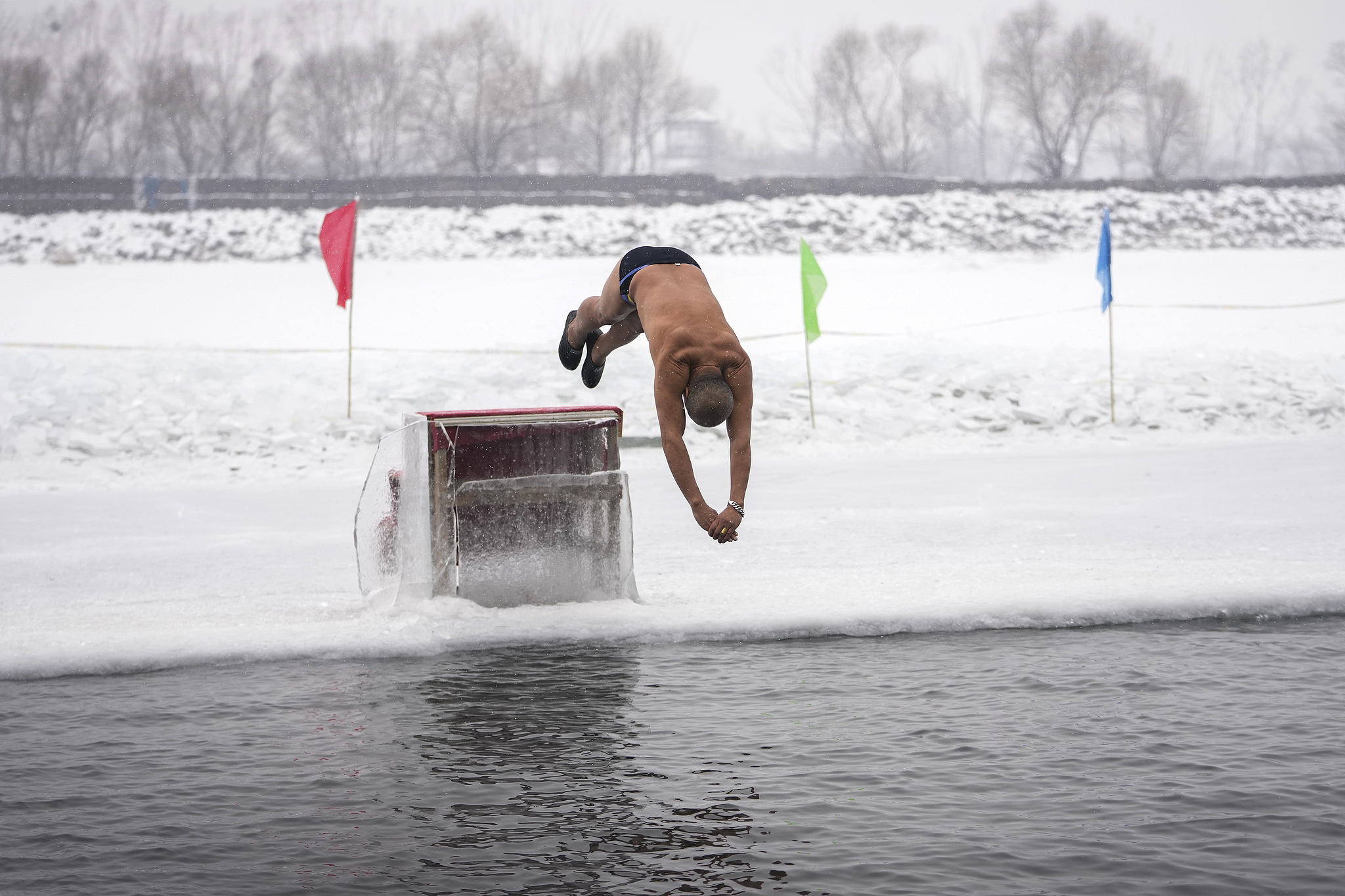 A man jumps into a pool carved out of the frozen Songhua River in Harbin, Heilongjiang Province on January 7, 2025. /Andy Wong/AP/VCG