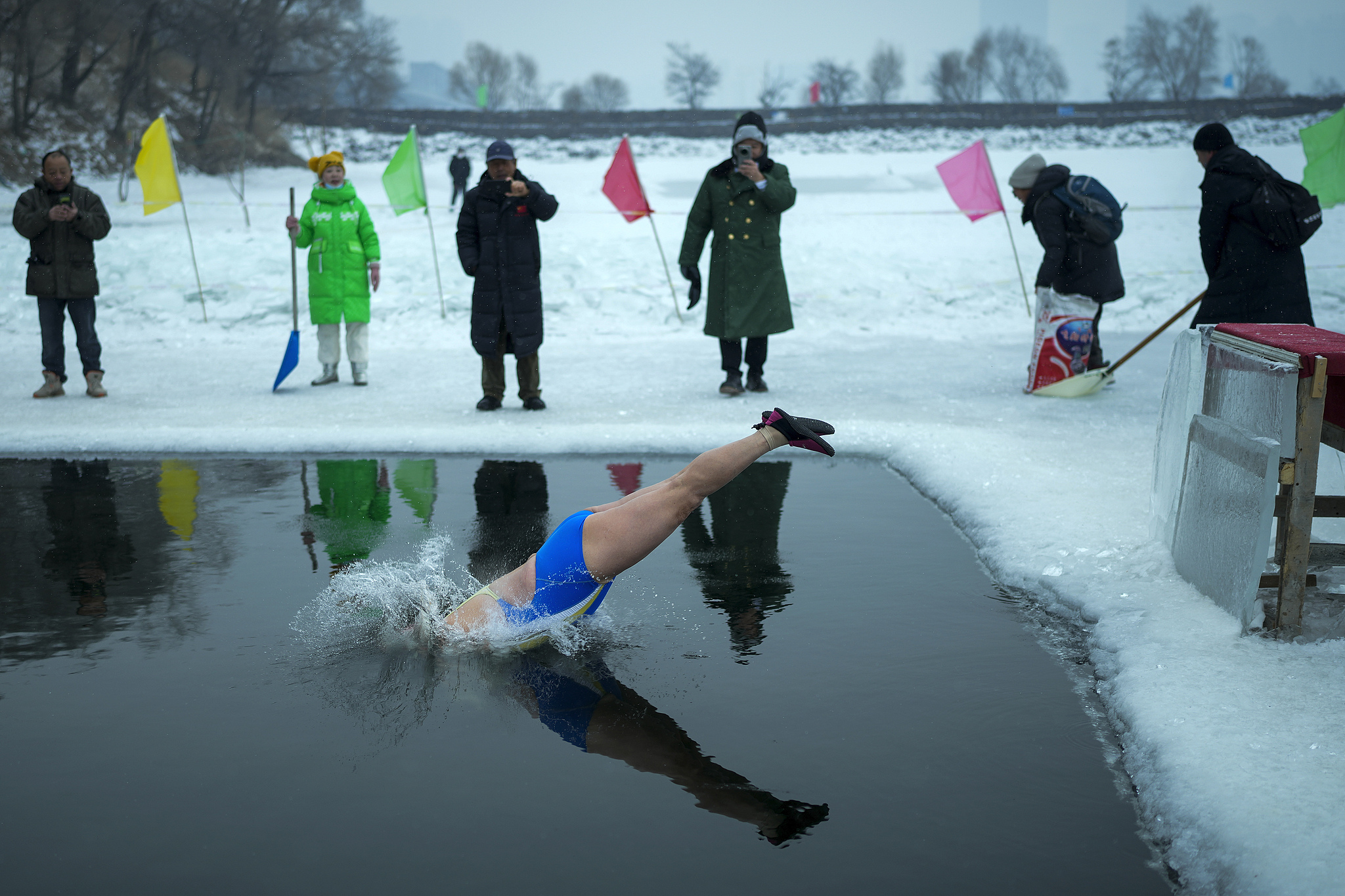 A woman jumps into a pool carved out of the frozen Songhua River in Harbin, Heilongjiang Province on January 7, 2025. /Andy Wong/AP/VCG