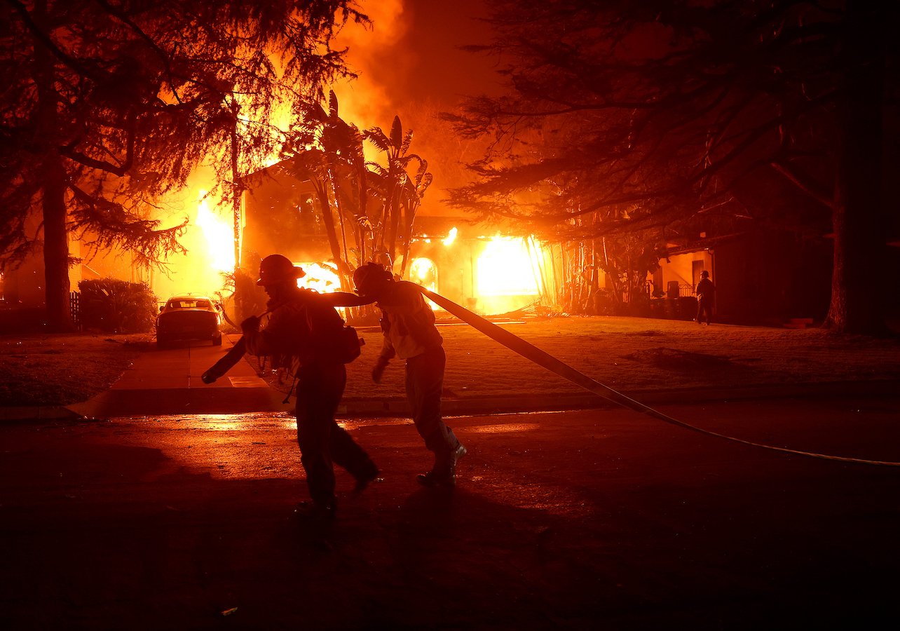 Los Angeles County firefighters pull a hose in front of a burning home as the Eaton Fire moved through the area in Altadena, California, U.S., January 8, 2025. /CFP